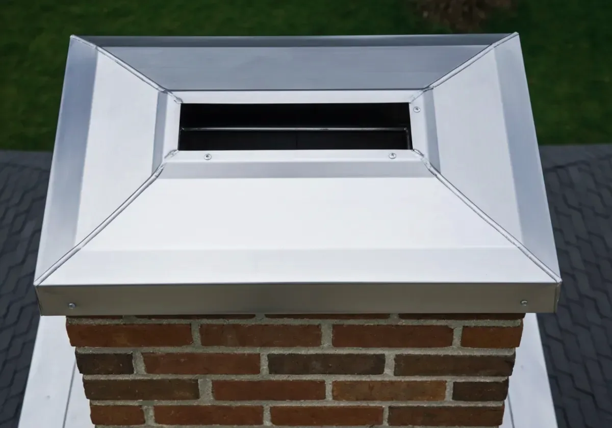After — chimney cap installation: An open flue closed off with a fitted stainless cap — rain and animals out, draft intact.